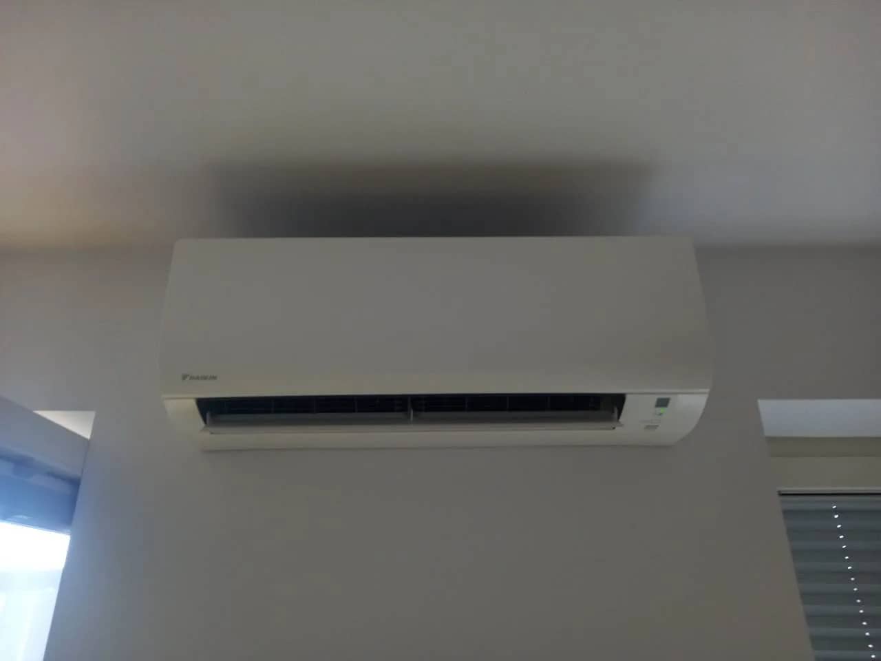 Biały klimatyzator ścienny w gotowym pomieszczeniu biurowym przy oknie z żaluzją