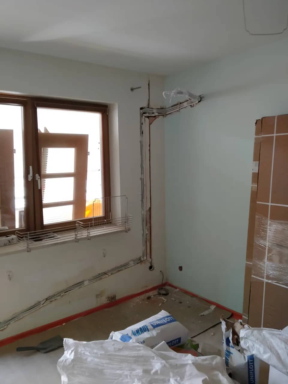 Pokój ze skutymi ścianami i bruzdami, drewniane okno, materiały budowlane na podłodze