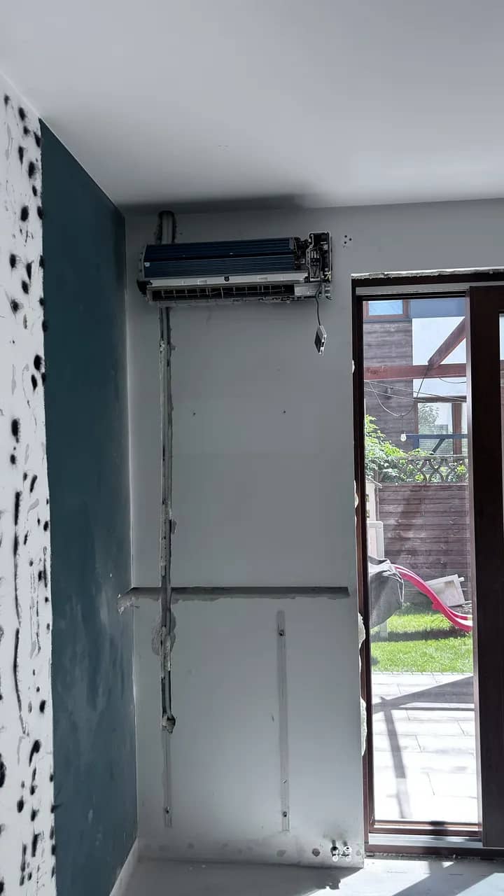 Jednostka split bez przedniego panelu nad instalacją poprowadzoną w ścianie