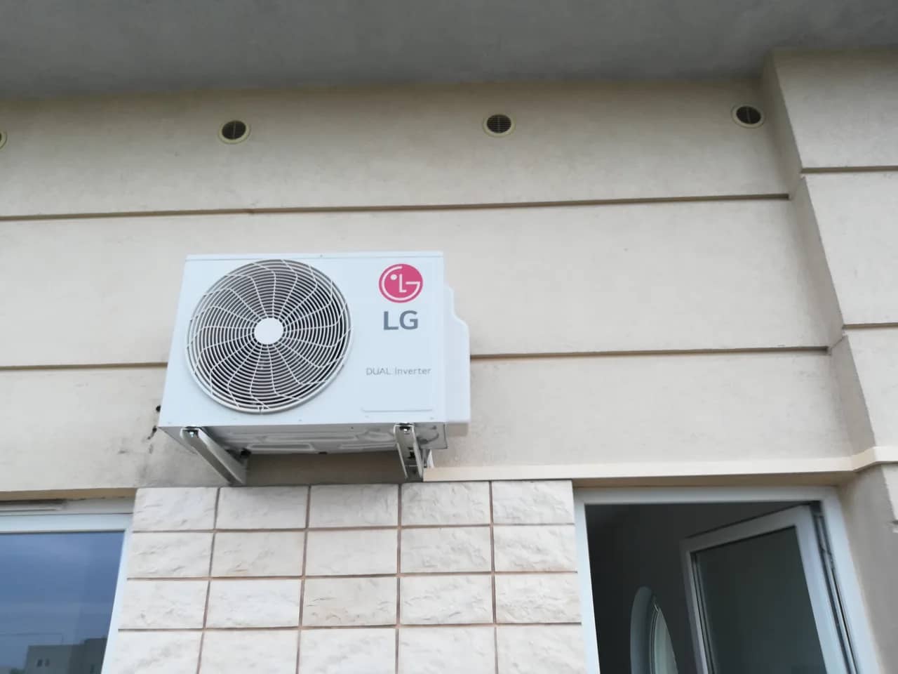 Jednostka zewnętrzna LG Dual Inverter zamontowana na wsporniku nad murkiem wyłożonym płytkami