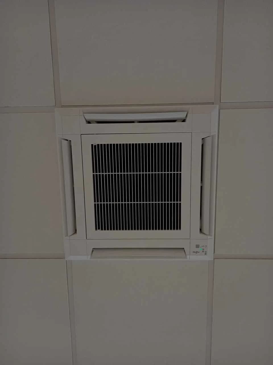 Kaseta sufitowa klimatyzacji wpuszczona w raster sufitu podwieszanego, widok z dołu