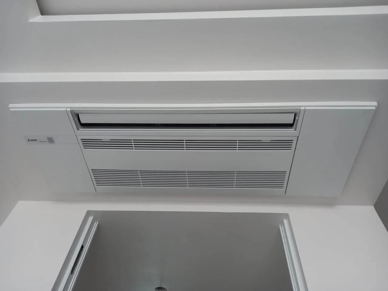 Kaseta klimatyzacji wpuszczona w wąski fragment sufitu z płyty przy ścianie