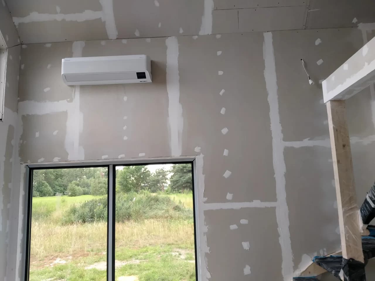 Klimatyzator na ścianie pokoju z płyt gipsowo-kartonowych ze szpachlowanymi łączeniami