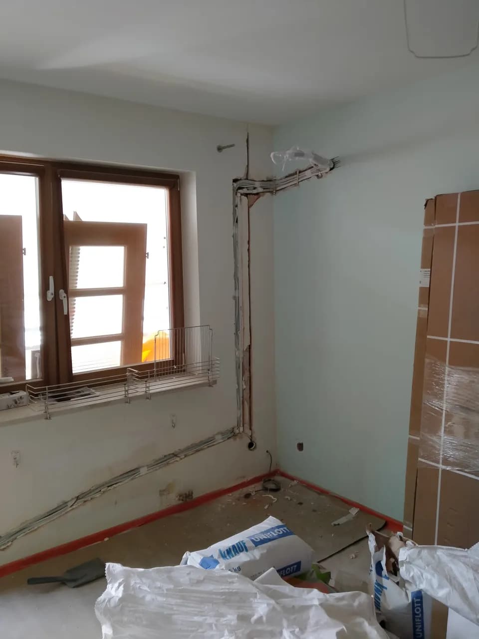Pokój ze skutymi ścianami i bruzdami, drewniane okno, materiały budowlane na podłodze