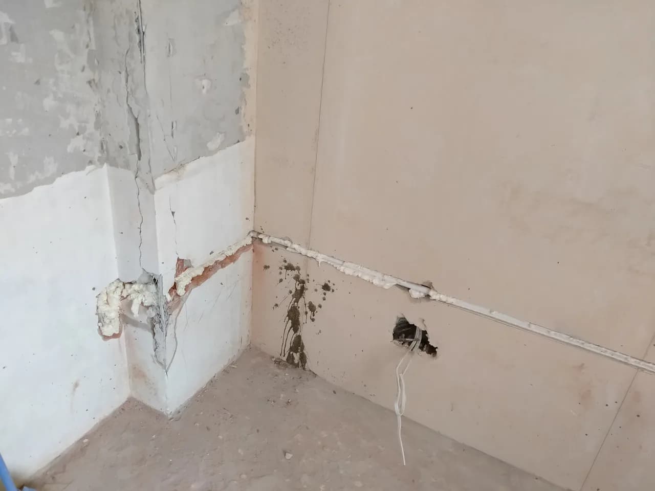 Fragment ściany z odbitym tynkiem i poprowadzoną w bruździe instalacją chłodniczą