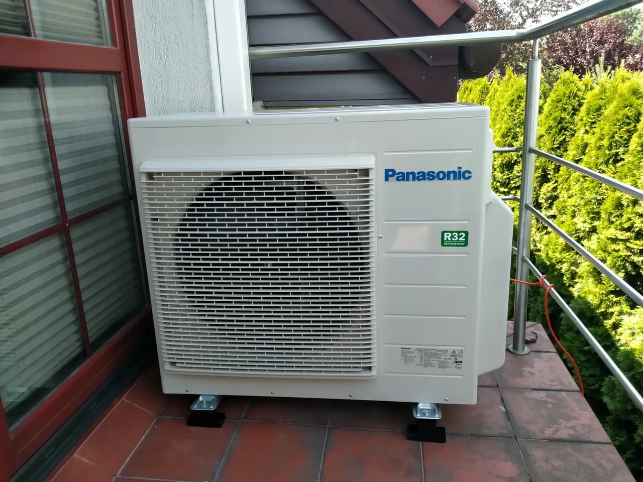 Jednostka zewnętrzna Panasonic R32 ustawiona na tarasie z terakotą przy metalowej balustradzie