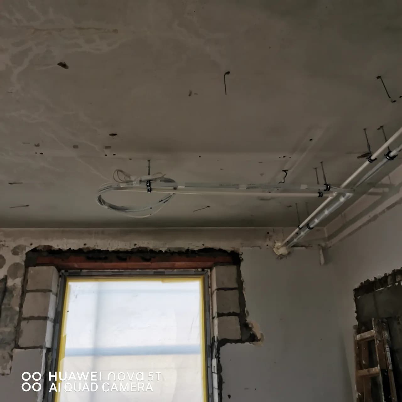 Instalacja chłodnicza schodząca po ścianie przy otworze okiennym w budynku w budowie