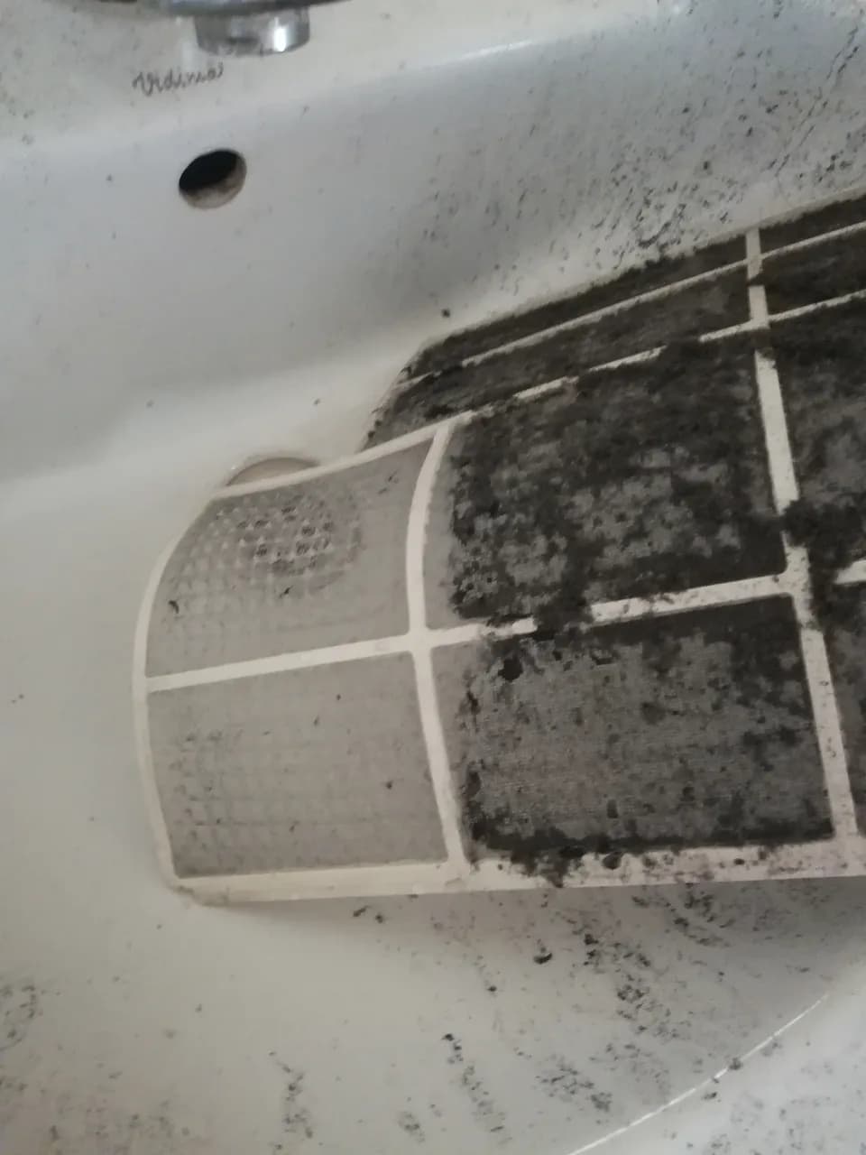 Zabrudzone filtry klimatyzatora leżące w umywalce, pokryte grubą warstwą kurzu