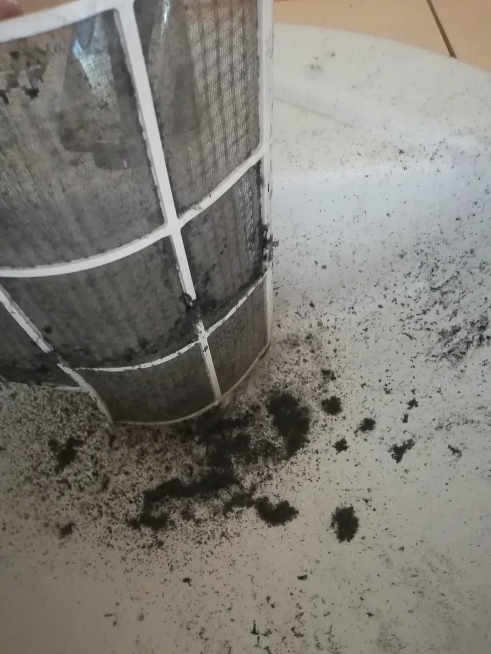 Filtr klimatyzatora w trakcie mycia, obok osad kurzu zmyty do umywalki
