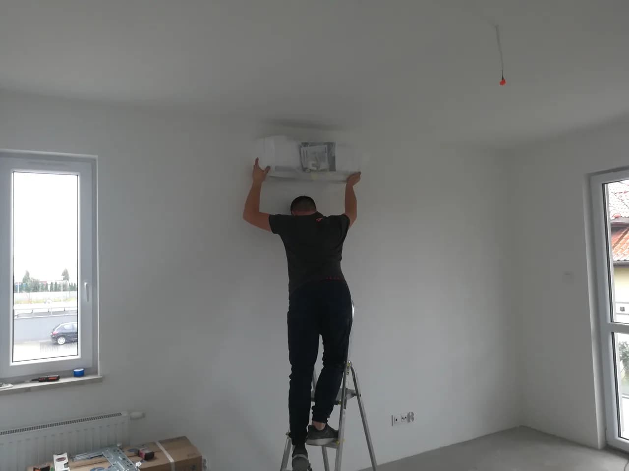 Monter przykładający jednostkę wewnętrzną klimatyzacji do ściany pokoju w domu w budowie