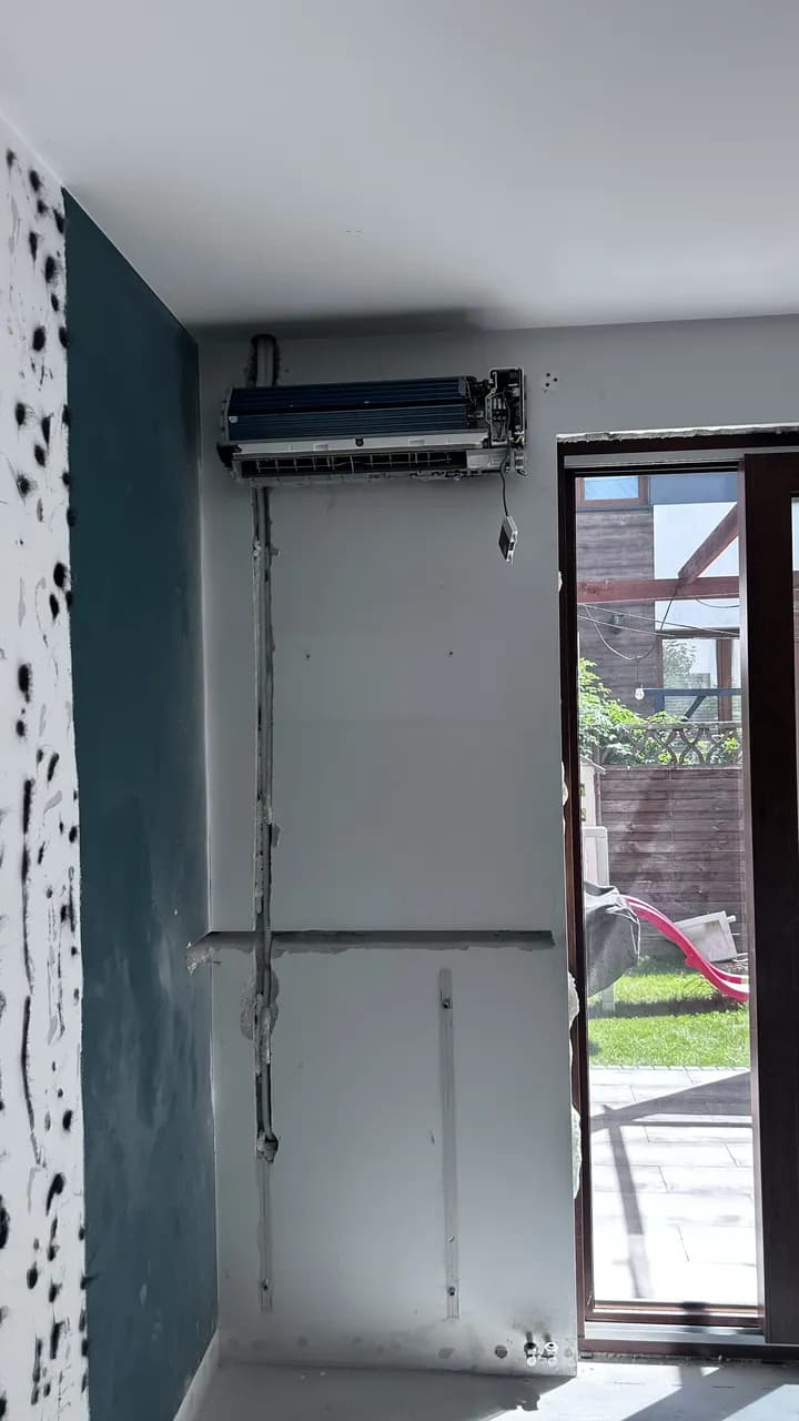 Jednostka split bez przedniego panelu nad instalacją poprowadzoną w ścianie