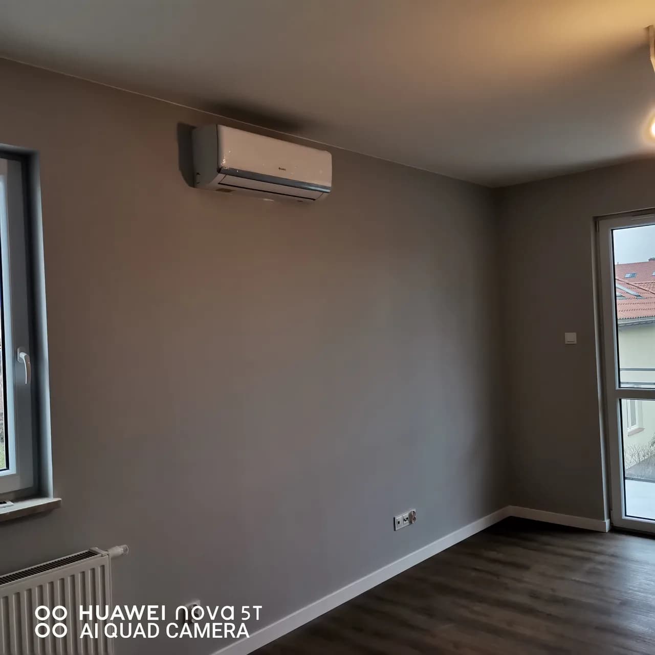 Klimatyzator ścienny w narożniku pokoju z oknem i wyjściem na balkon